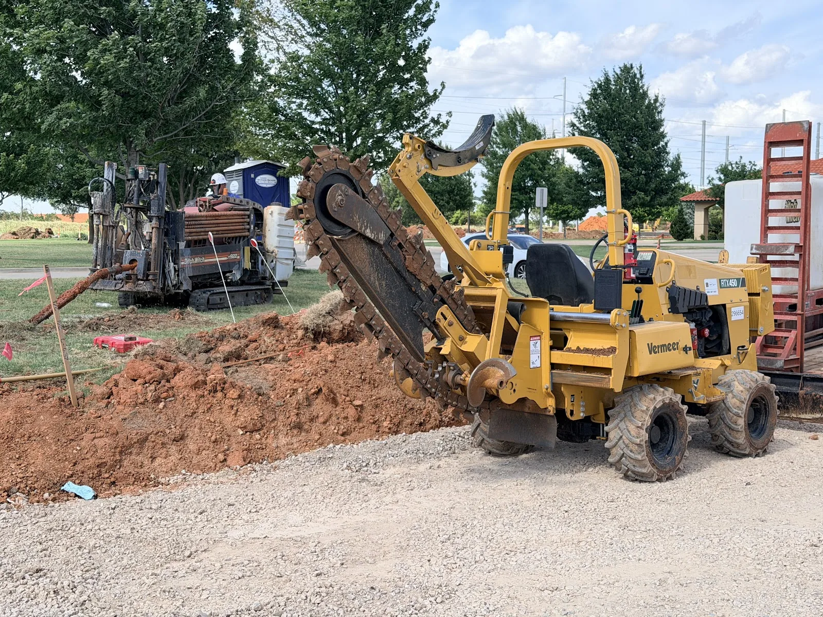 Trencher cutting an open utility trench on a Dallas property