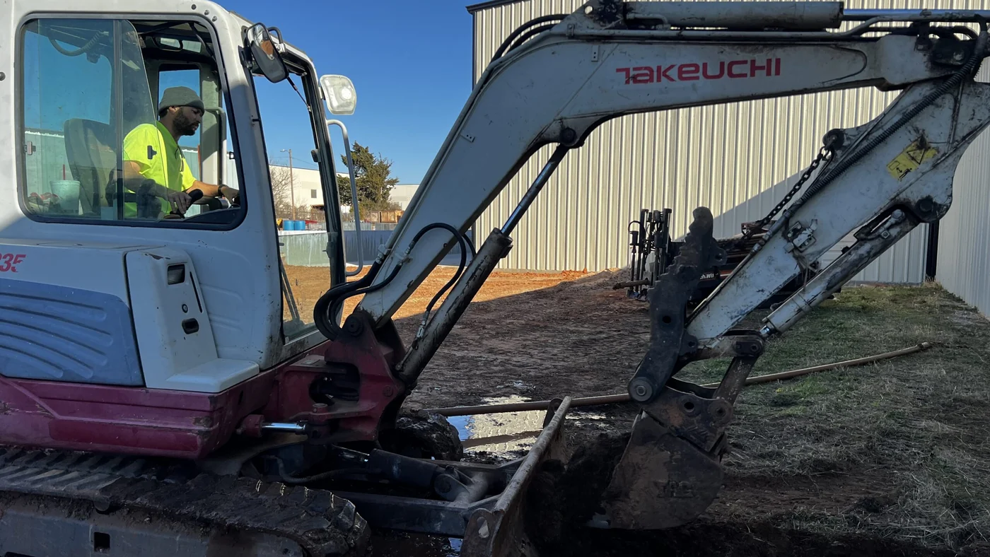 Mini-excavator opening a clean bore pit to tie in new underground utilities, Dallas Texas